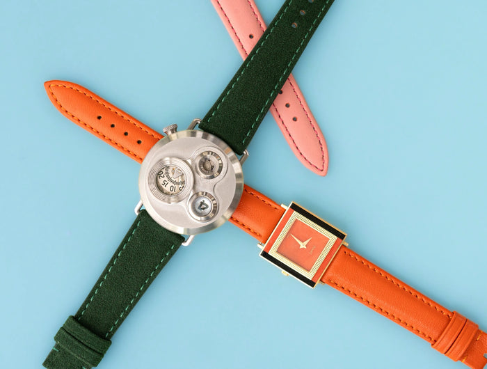 Zwei Uhren mit grünen, orangefarbenen und rosafarbenen Uhrenarmbändern