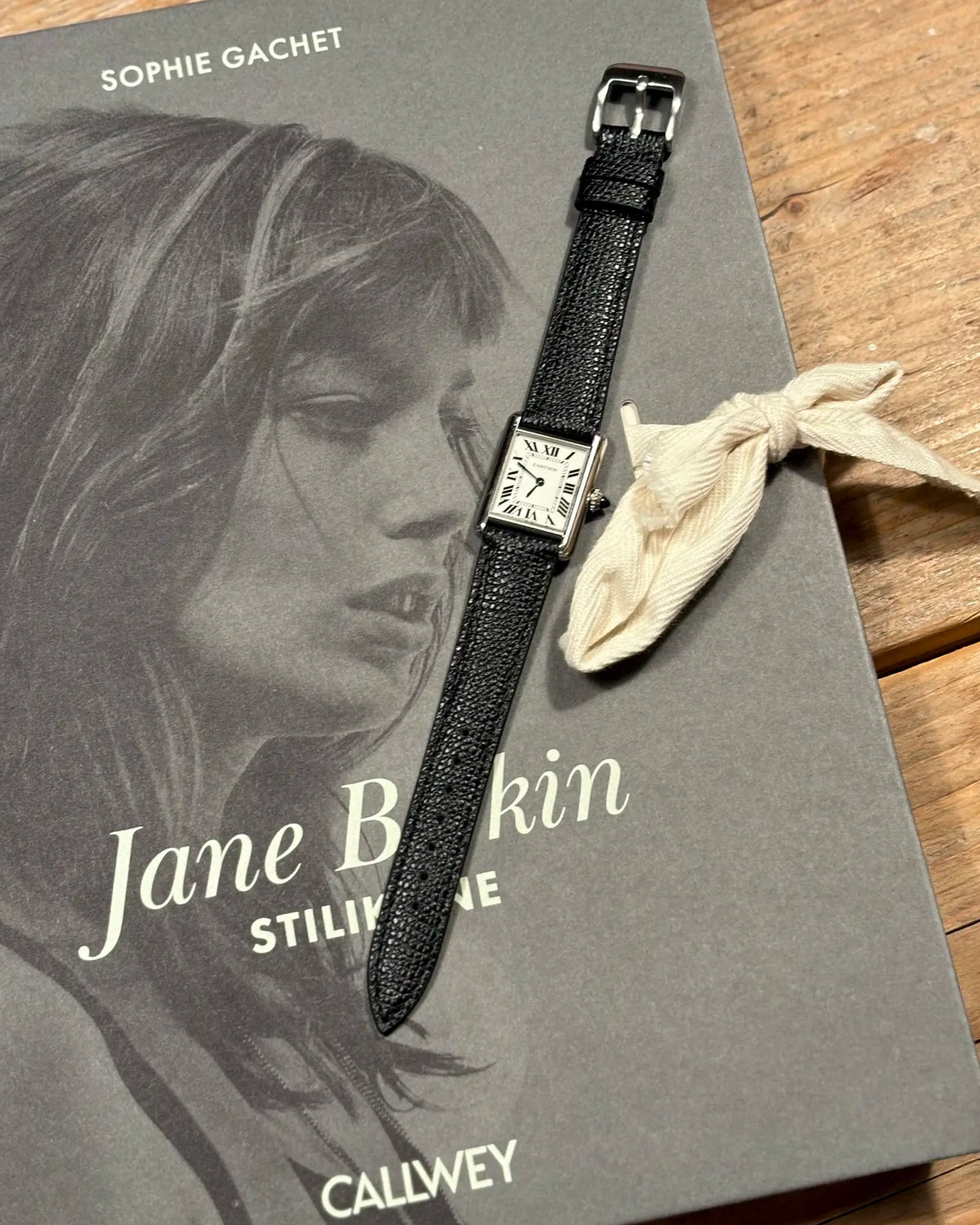Rindsleder French Style 9 to 5 an der Cartier Tank Must SolarBeat Small auf einem Bildband