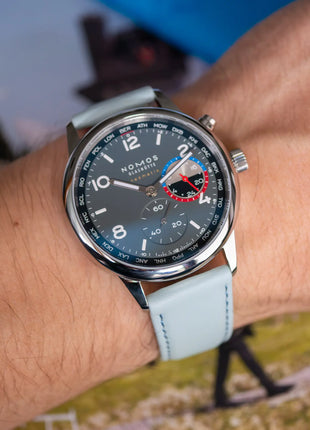 Kalbsleder Classic Fresh an NOMOS Club Sport neomatik Weltzeit Volcano – Lifestyleaufnahme am Handgelenk